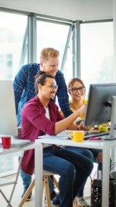 Oficina amb tres empleats mirant l’ordinador