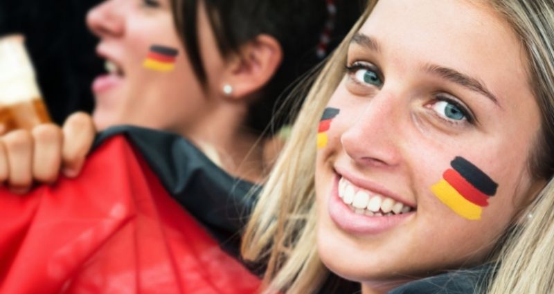 Noia rossa i amb ulls blaus somrient a la càmera amb la bandera alemanya pintada a la galta