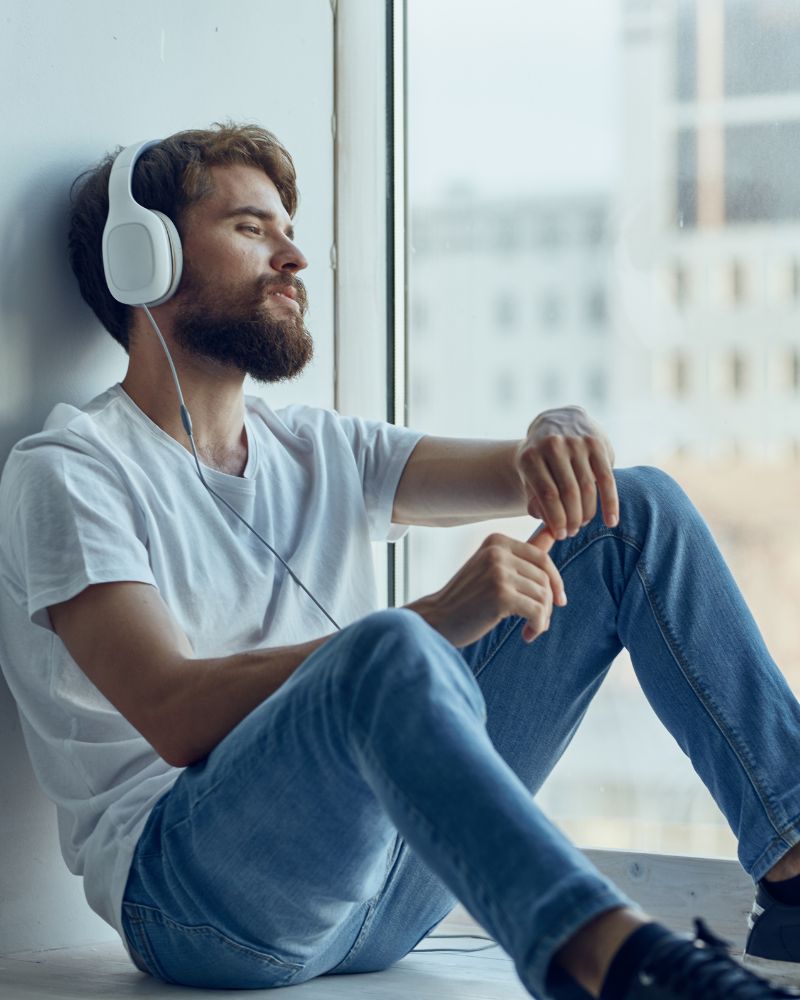 Young man inlingua Andorra student with headphones next to a window